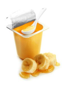 Tasty dessert in open plastic cup and banana, isolated on white