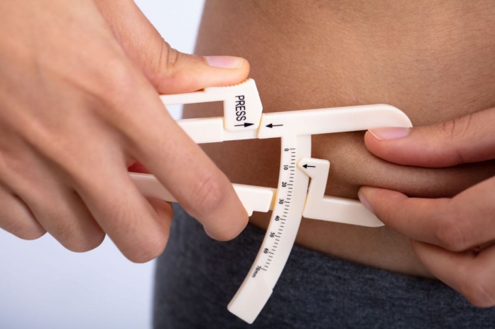 woman measuring body fat with calipers